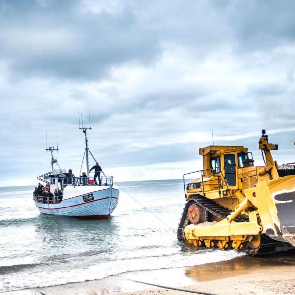 Bulldozer trækker fiskekutter i land