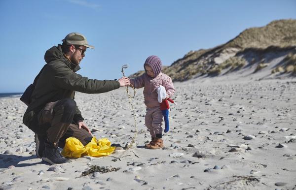 Far og datter samler affald på stranden